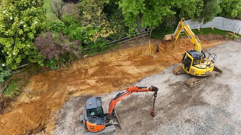 Excavators working on a residential site alongside retaining works in Auckland - Bromley Group